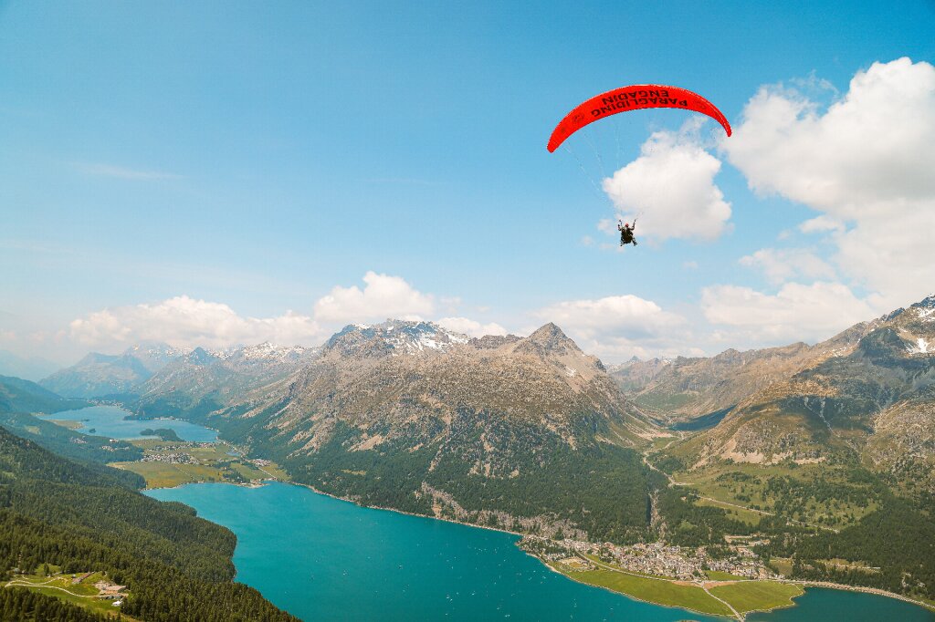 Ein gleitschirm von Paragliding Engadin fliegt über die Seenlandschaft von Silvaplana.