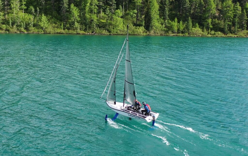Die foil Jolle von Lakefly fliegt über den türkisfarbenen Silvaplanersee.